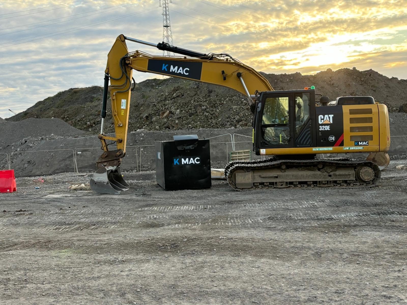 KMAC-branded excavator on site at sunset